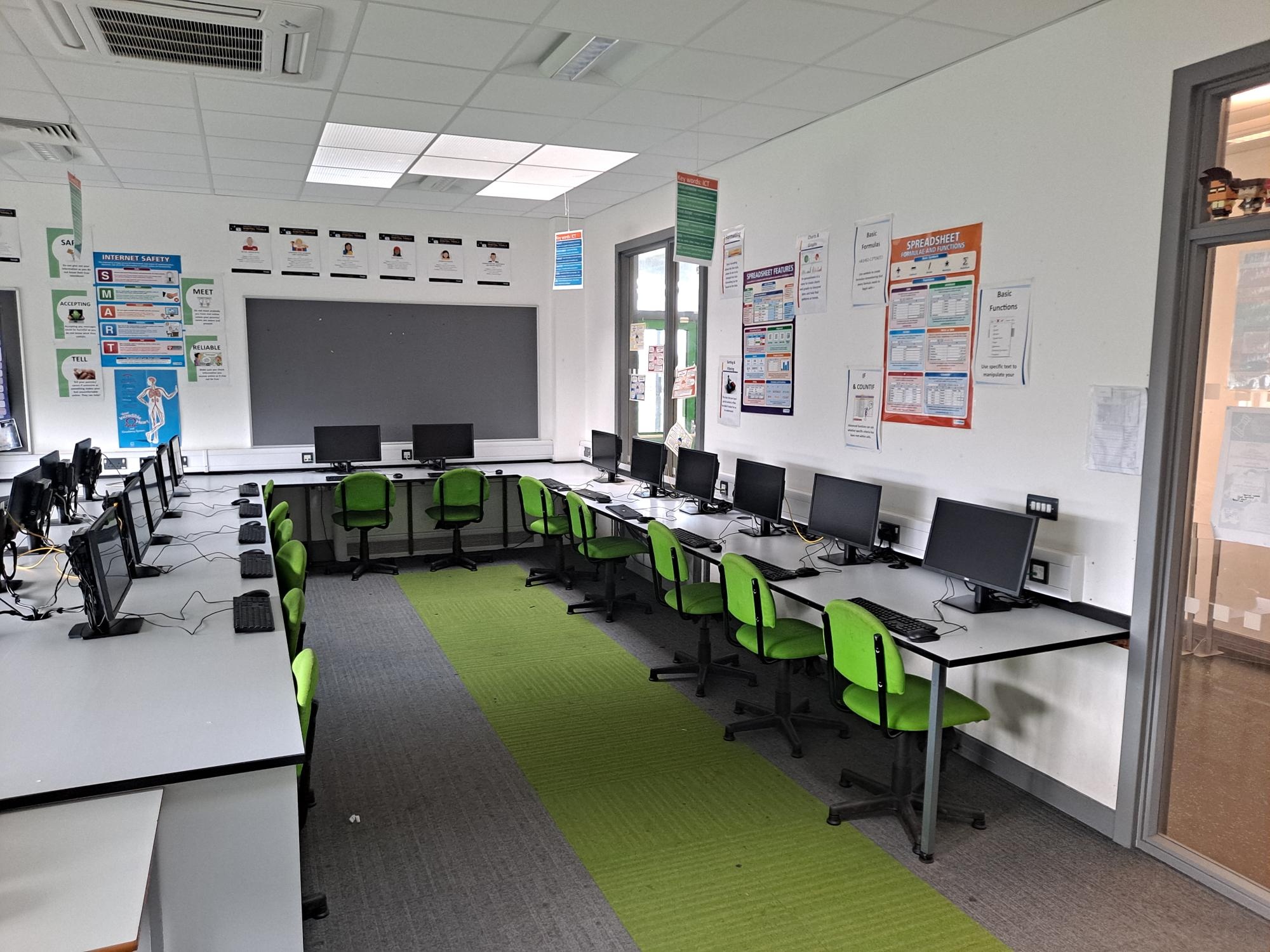 Modern school ICT classroom with green and black chairs and computer workstations, managed by Penk Valley Academy Trust.